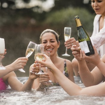 A group of women drinking champagne in a hot tub.